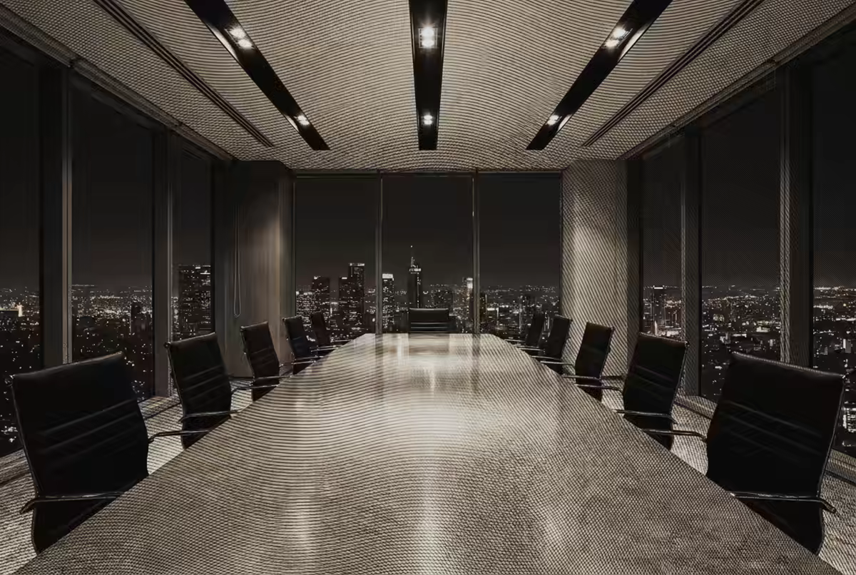 Una sala de comité vacía, con la mesa larga bajo la luz y la ciudad al fondo.