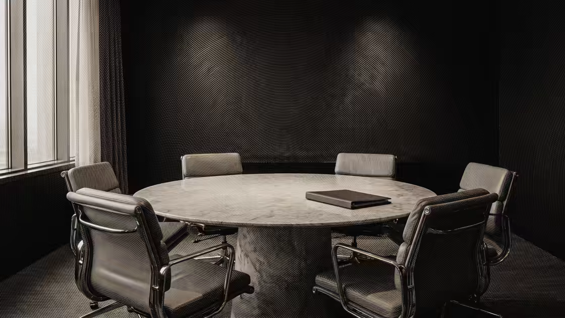 Una sala de reuniones con una mesa redonda de piedra y una carpeta cerrada encima